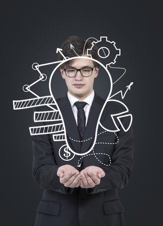 businessman holding lightbulb with chart and gearsの写真素材