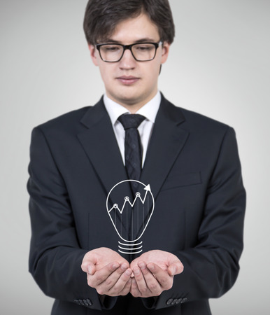 businessman in office holding lightbulb with chartの写真素材