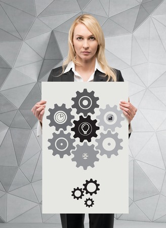 businesswoman holding placard with cogwheel and gearsの写真素材