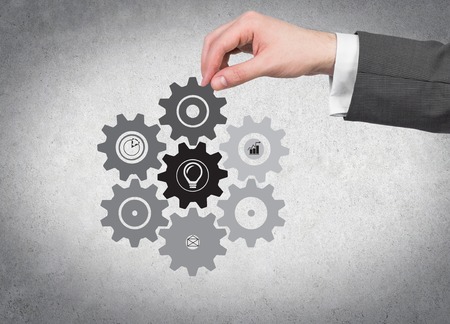 hand holding cogwheel and gears on wall の写真素材