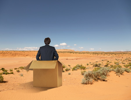 businessman sitting in box and loocing to desertの写真素材
