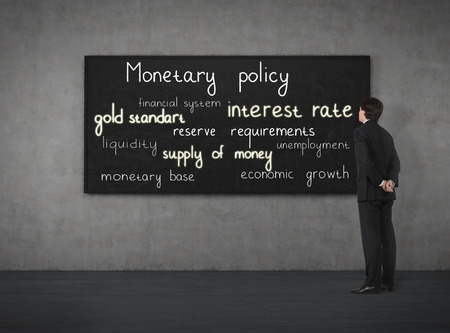 Businessman looking to monetary policy at the blackboardの写真素材