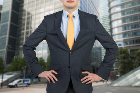 Businessman in suit and yellow tie on skyscraper backgroundの写真素材