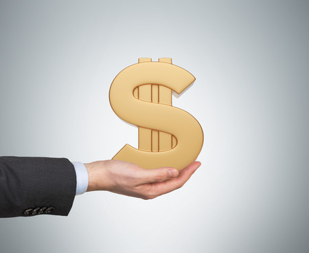 hand holding gold dollar symbol isolation on grayの写真素材