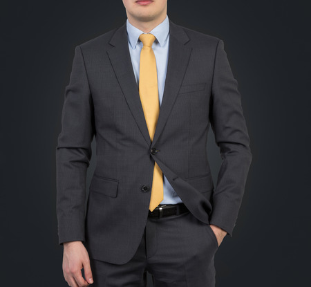 Businessman in suit and yellow tie on a black backgroundの写真素材