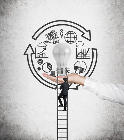 Businessman climbs the stairs on hand with lampの写真素材
