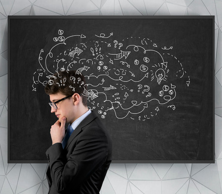 young businessman thinking with arrows and lamp over headの写真素材