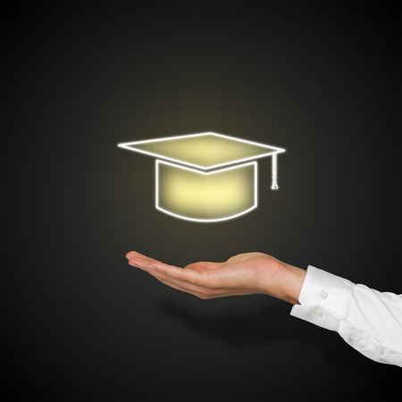 hand holding bachelor cap on black backgroundの写真素材