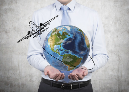 businessman holding Planet with flying airplaneの写真素材