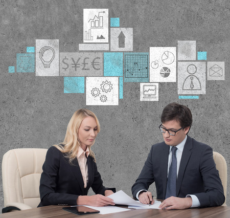 two businesspeople working in office with drawing business iconsの写真素材