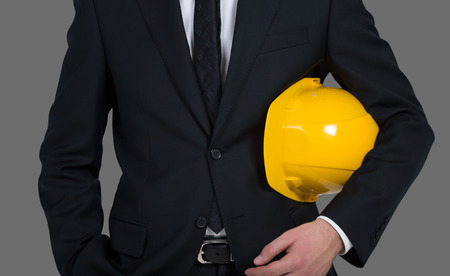 engineer holding yellow helmet for workers security on gray background