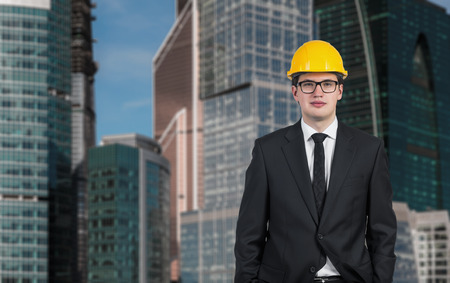 businessman in yellow helmet on skyscraper backgroundの写真素材