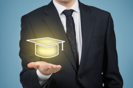 businessman holding gold bachelor hat isolation on blueの写真素材