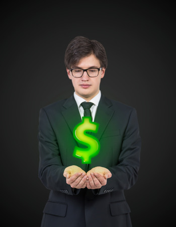 businessman holding green dollar on a black backgroundの写真素材