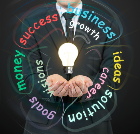 businessman holding bulbs on a black backgroundの写真素材