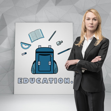 woman student standing near poster with education symbolの写真素材