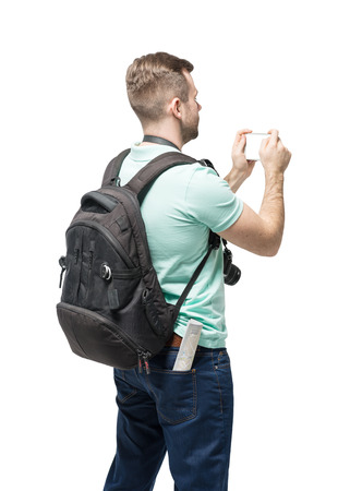 Young man with backpack taking a photo over white backgroundの写真素材