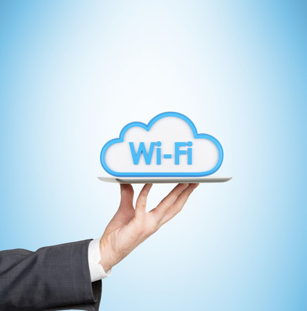 A hand is holding a tablet with the icon of the wifi cloudの写真素材