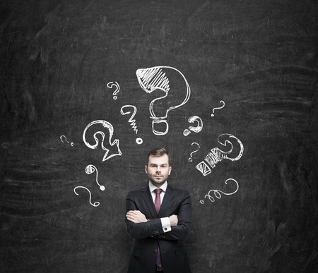 Handsome young businessman is standing surrounded by arrows in different direction. の写真素材