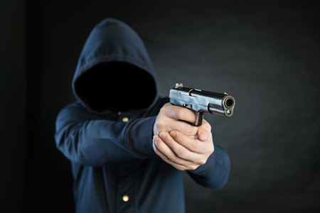 Armed person in a hoodie is pointing a handgun at the target.の写真素材