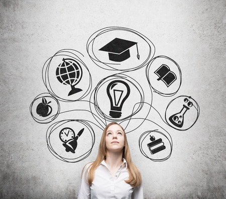 Young beautiful business lady is thinking about getting degree at the university. Drawn the range of the educational icons over the concrete wall. Graduation hat.