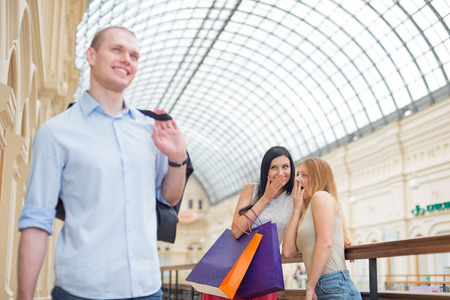 Smiling girls and a man with shopping bags in a luxury central shop. Shopping, sale, gifts and holidays concepts. High-street shopping.の写真素材