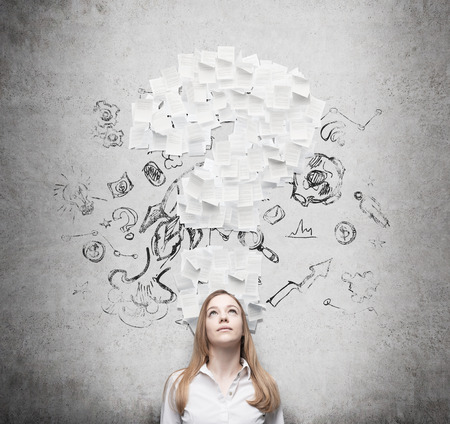 Business woman is thinking about the question mark which consists of the contract pages.の写真素材