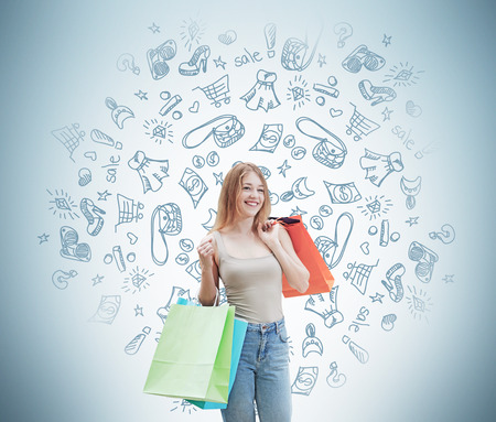 A happy young woman with the colourful shopping bags from the fancy shops. Shopping icons are drawn on the wall.の写真素材