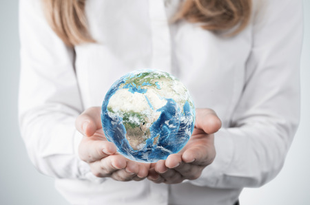 Close-up of blonde's hands who holds the globe with Africa, Europe and Asia hemisphere. A woman dressed in formal clothes. A light grey background. Elements of this image furnished by NASA.の写真素材