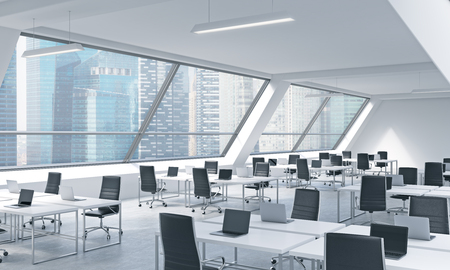 Workplaces in a bright modern open space loft office. White tables equipped by modern laptops and black chairs. Singapoere panoramic view in the windows. 3D rendering.の写真素材