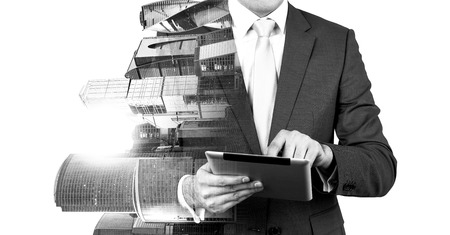 An abstract transparent businessman is looking something in the tablet. Moscow city business centre view. Black and white image.の写真素材