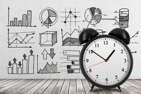There are different business charts on the concrete wall. An alarm clock is settled on the front view of the photograph. 3D rendering. Wooden floor.の写真素材
