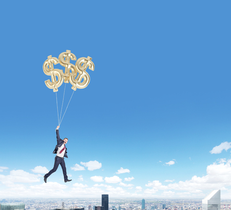 businessman in a suit flying happily holding three balloons in shape of dollars over new york, bright blue sky, concept of success and career growthの写真素材