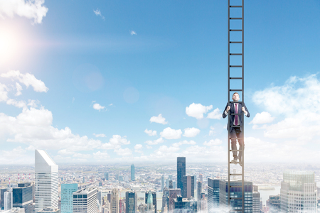 A young businessman in a suit climbing a ladder, Paris view and blue sky at the background. Concept of career development.の写真素材