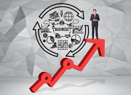 A young man standing and thinking on a thick red growing graph looking in front with his hands in front, a picture of business cycle behind. Grey geometric background. Front view. Concept of success.の写真素材