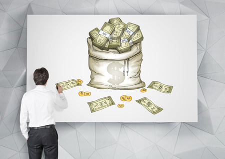 young man painting a picture of a bag of money on a white board. Back view. Grey geometric background. Concept of having a lot of money.の写真素材