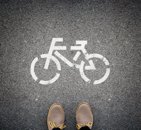 Two brown boots standing on asphalt in front of a picture of a bike. Top view. Concept of eco traveling.の写真素材