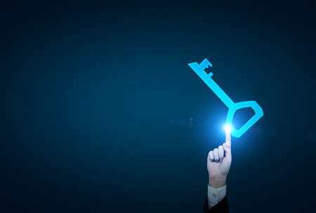 A hand touching a blue key which gets activated. Blue background. Concept of finding a solution.の写真素材