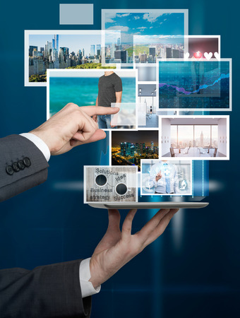 A hand holding a tablet, the other hand pointing at one of the pictures over it. Blue background. Concept of choice.の写真素材