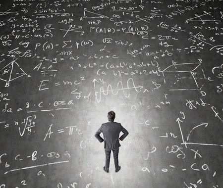 A businessman with hands on hips standing on the black floor, graphs and formulas around him. Top view. Concept of solving a problem.の写真素材