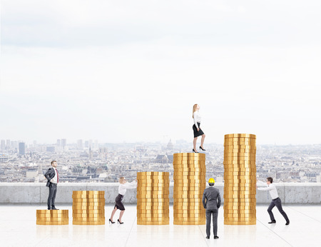Several big rouleaus of coins, a man and a woman standing on two of them, two others pushing rouleaus to each other, a businessman looking at them. Roof, Paris at the background. Concept of workの写真素材