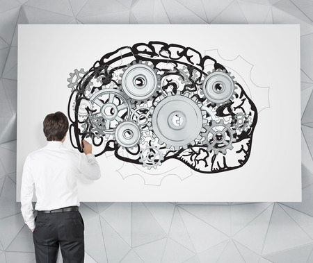 Businessman drawing image of brain with gears on white poster. Back view. Grey background. Concept...