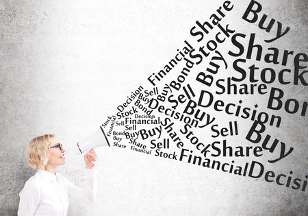 Businesswoman holding white loudspeaker, many business words from it. Concrete background. Concept of informing.の写真素材