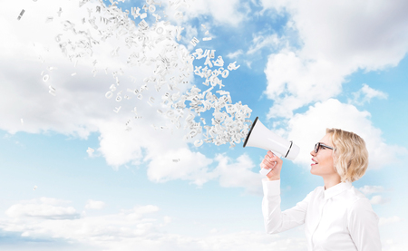 Beautiful woman with white loudspeaker, letters flying from it. Side view. Sky at background. Concept of informing.の写真素材