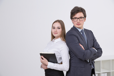 Businesswoman and businessman standing side by side. Office at background. Concept of cooperation.の写真素材
