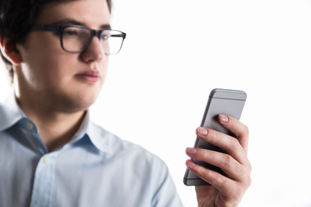 Businessman in glasses looking at smartphone screen. White background. Concept of communication.の写真素材