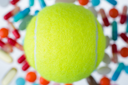 Tennis ball, many coloured pills of different size at background. Concept of medicine. Mock up. 3D renderingの写真素材