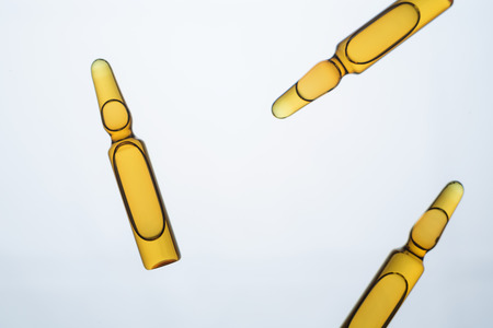 Three amber-colored ampoules isolated on light backgroundの写真素材