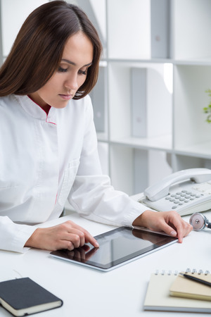 Female doctor using tablet at desk in officeの写真素材