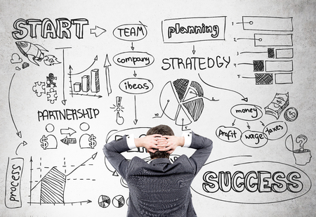 Research concept with stressed man looking at wall with business schemesの写真素材